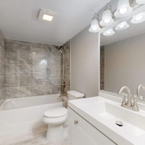 Elegant modern bathroom featuring marble tiles and sleek white vanity.