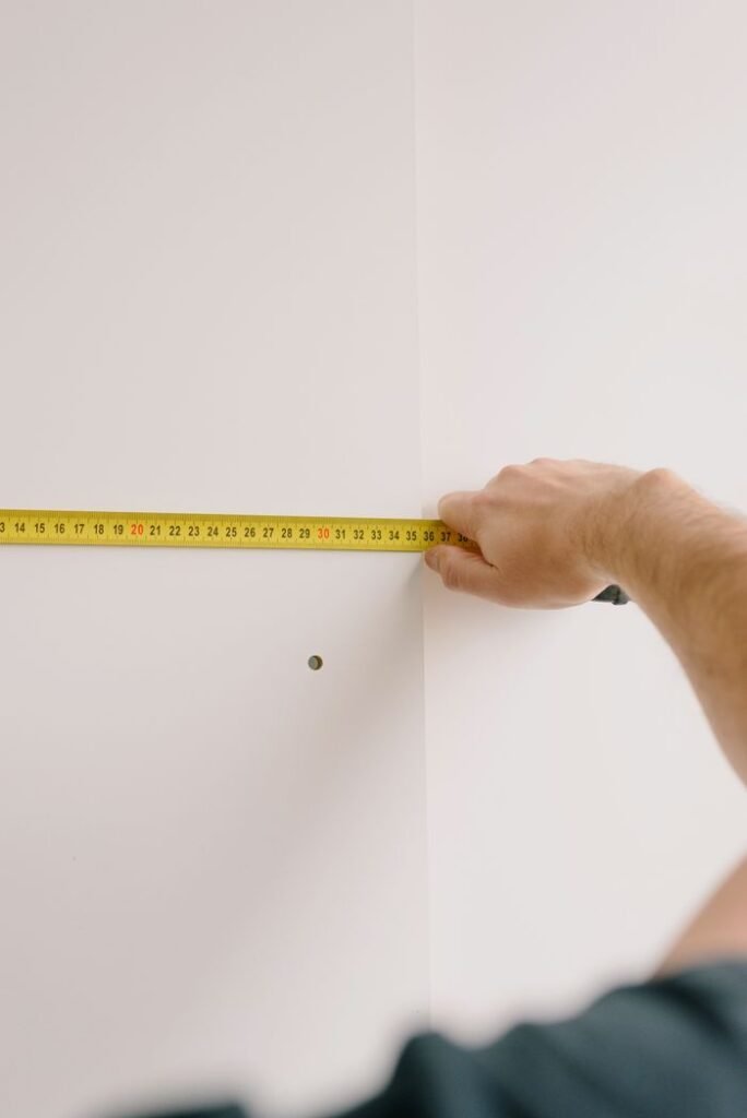 Home Crop unrecognizable male holding measuring tape while preparing for renovation works in room