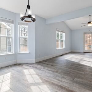 Bright empty living room with wooden floor and ceiling fan, ideal for interior design use.