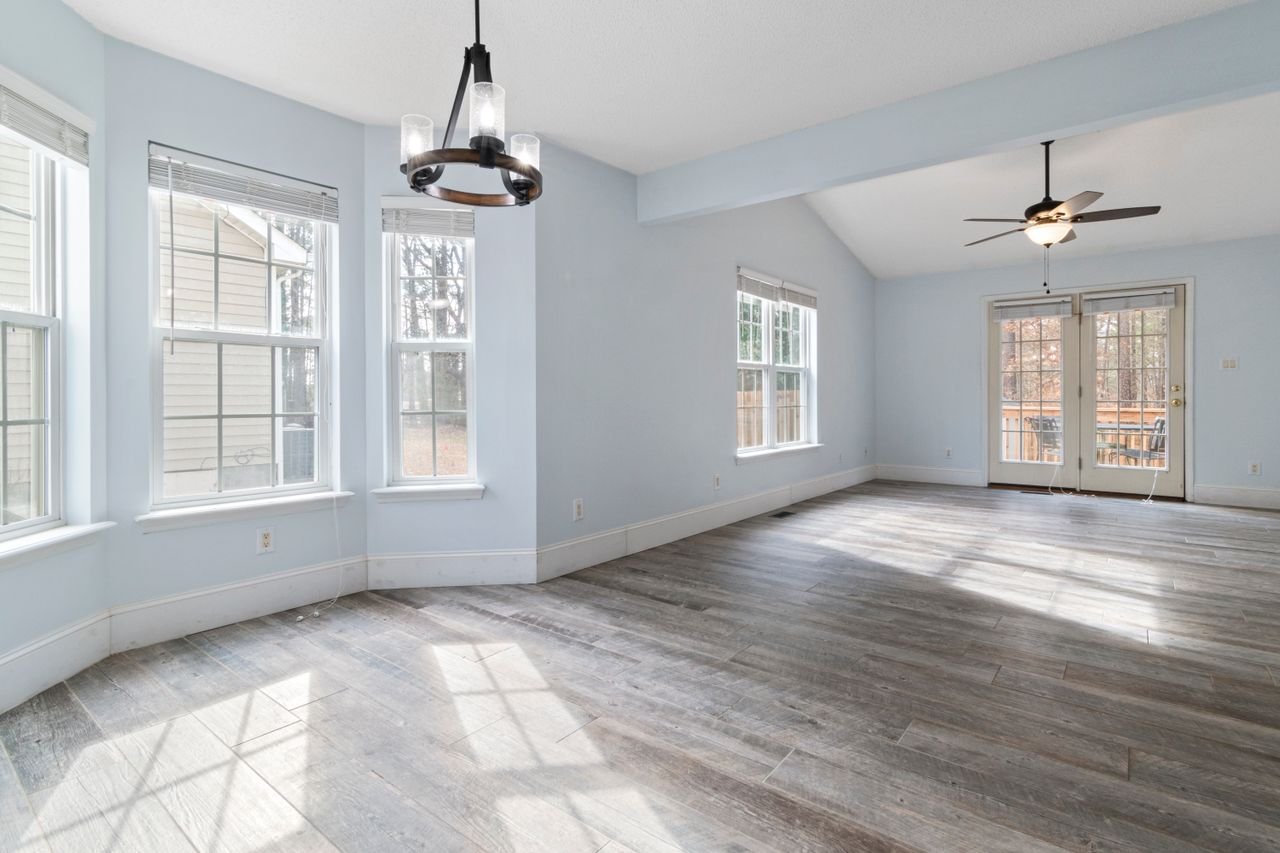 Bright empty living room with wooden floor and ceiling fan, ideal for interior design use.